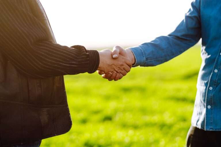 Handshake two farmer on the background of wheat field at sunset. Concept of agricultural business.